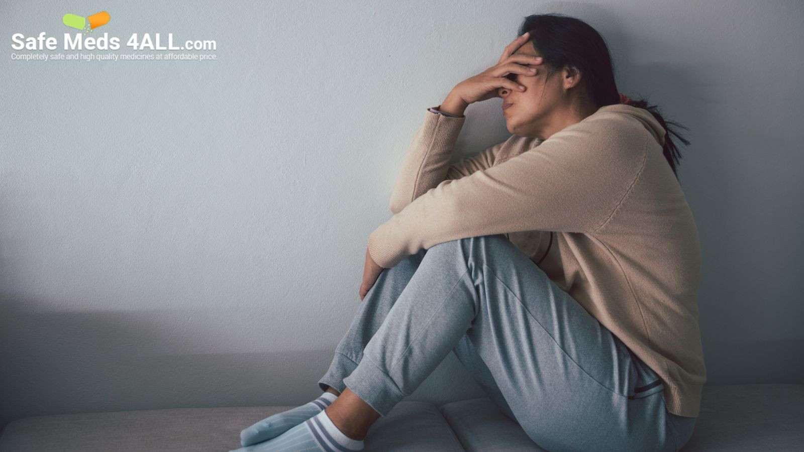 A woman on couch holding head in depression.